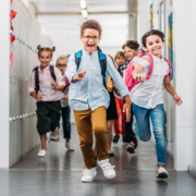 Parcours Formation | Éducateur, éducatrice en service de garde | Enfants qui courent dans un corridor avec leur sac à dos